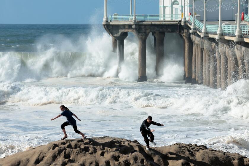 Manhattan Beach, California December 30, 2023-Children scramble as waves come crashing on shore next to the Manhattan Beach Pier Saturday. (Wally Skalij/Los Angeles Times)