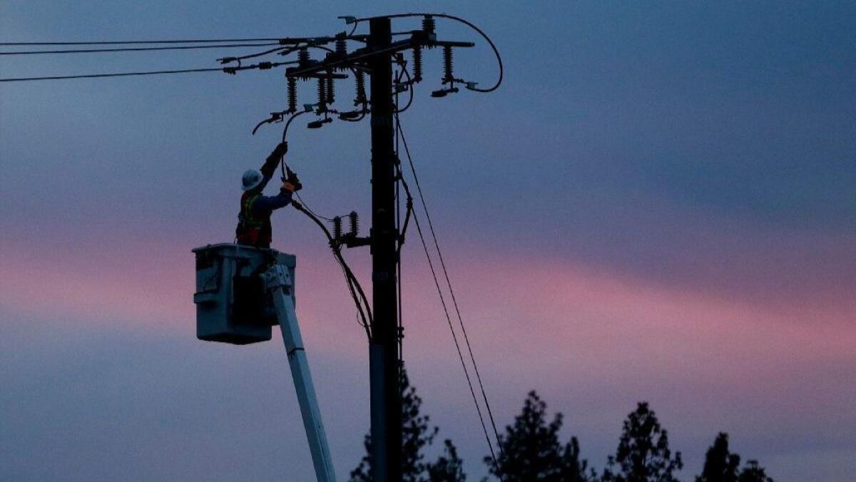 A Pacific Gas & Electric lineman works to repair a power line in fire-ravaged Paradise, Calif., on Nov. 26, 2018.