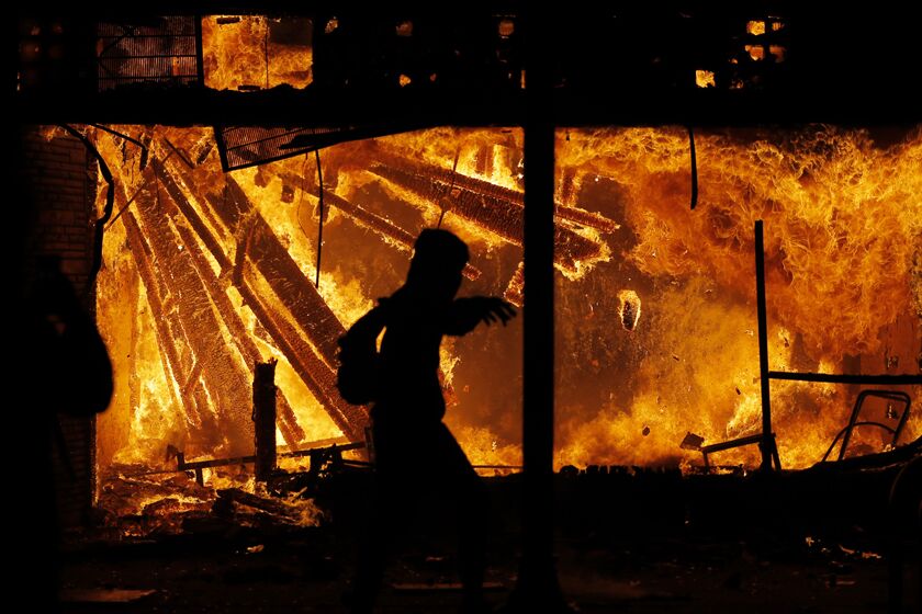 A protester runs in front of the burning police station in Minneapolis on Thursday night.