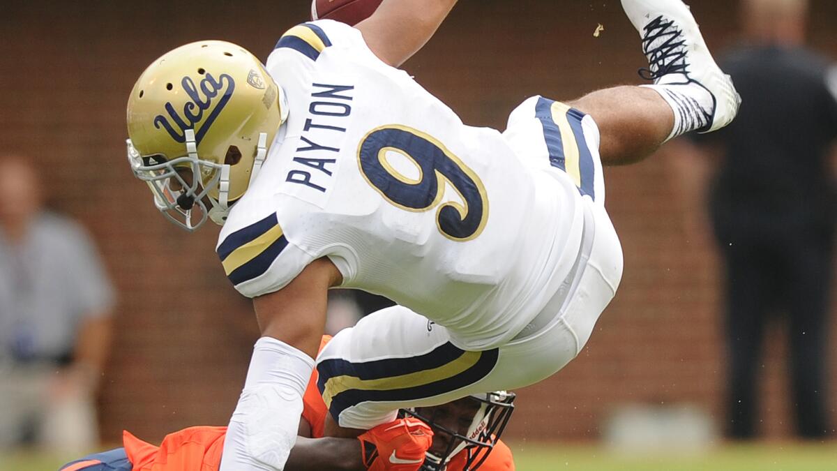 UCLA receiver Jordan Payton is upended by Virginia cornerback Tim Harris during the Bruins' 28-20 victory Saturday. The Bruins' offense looked unimpressive in the team's season opener.