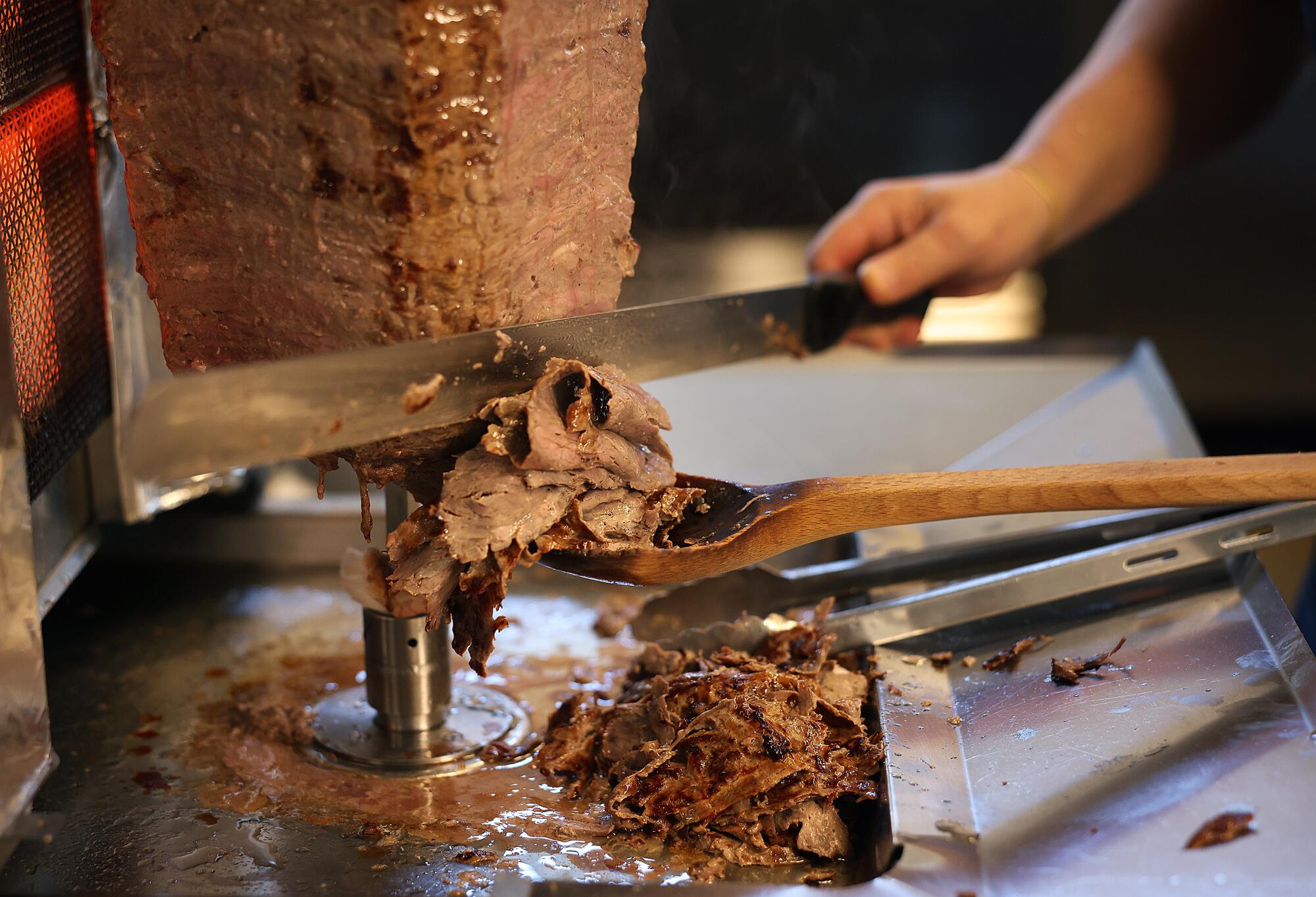 Hüsnü Kahramanoğlu slices döner kebab from a vertical spit stacked with layers of marinated beef and lamb.