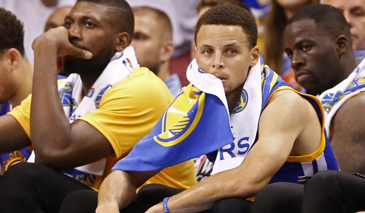The Golden State Warriors' Stephen Curry sits on the bench with a towel on his head in final seconds of the loss to the Oklahoma City Thunder of Game 4 of theNBA Western Conference finals Tuesday.