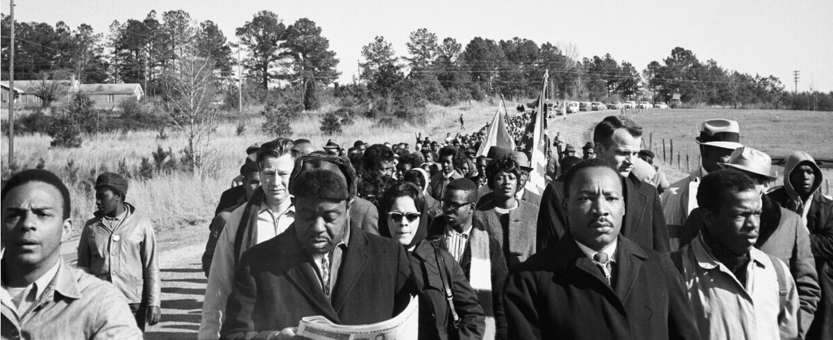A black-and-white image of a crowd of people marching.