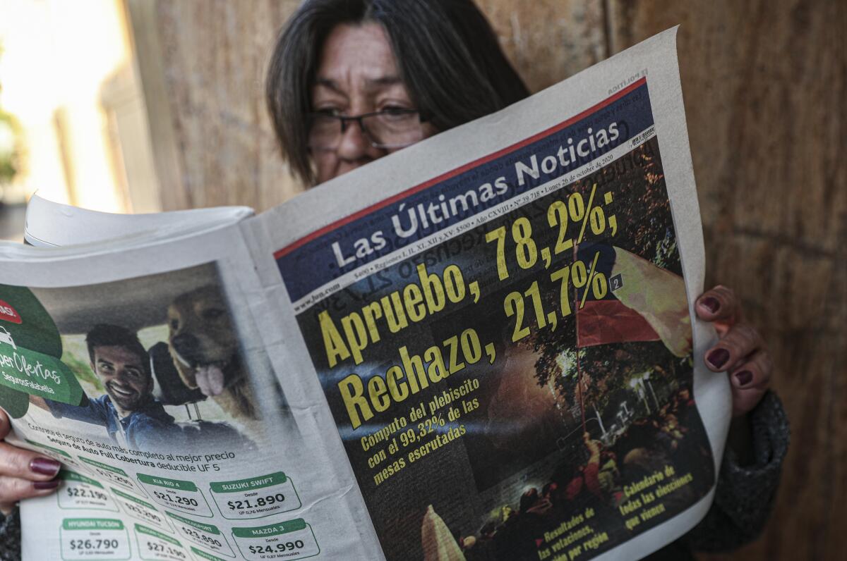 Una mujer lee un periódico que muestra los resultados del plebiscito del día anterior