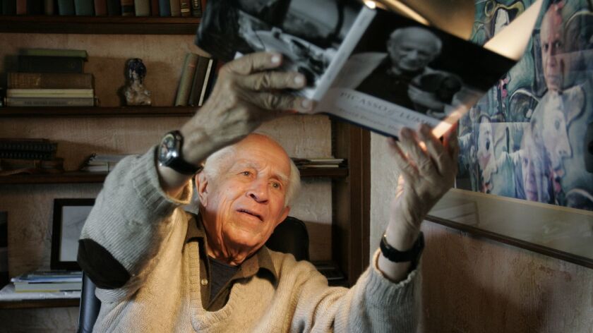 Photographer David Douglas Duncan holds an autographed copy of his book "Picasso and Lump" up to a lamp to dry the ink, at his home near Cannes, France, in 2006. Duncan died Thursday at 102.