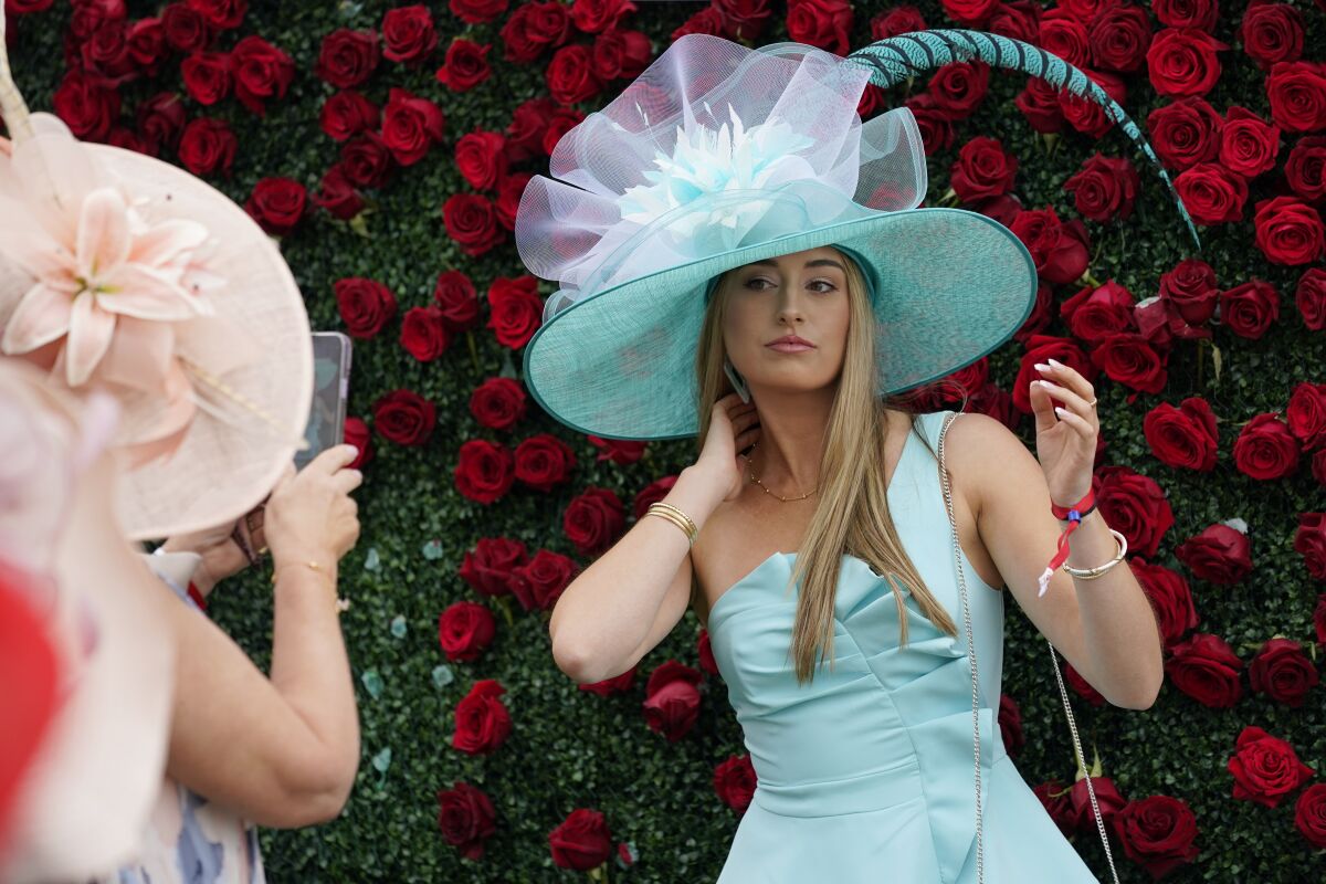 A fan poses in front of a wall of roses at Churchill Downs before the 148th running of the Kentucky Derby on Saturday.