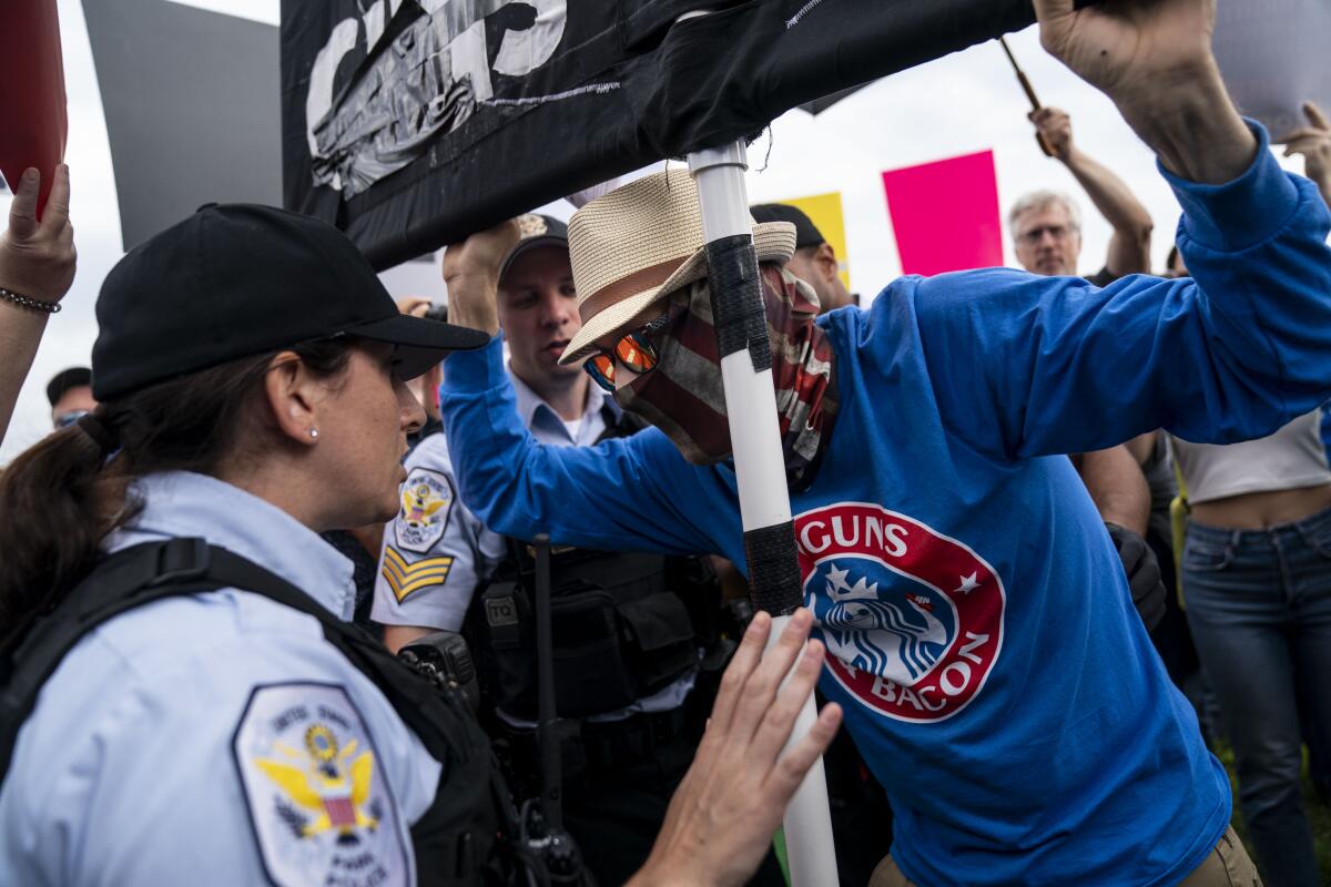 U.S. Park Police officers speak to a counterprotester holding a sign at Saturday's rally.