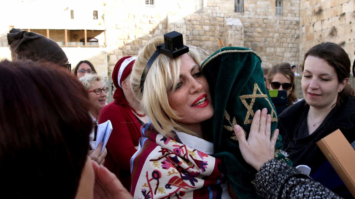 In 2016, a member of the liberal Jewish religious group Women of the Wall wears phylacteries and Tallit, a traditional Jewish prayer shawls for men, as she holds a Torah at the Western Wall in Jerusalem.