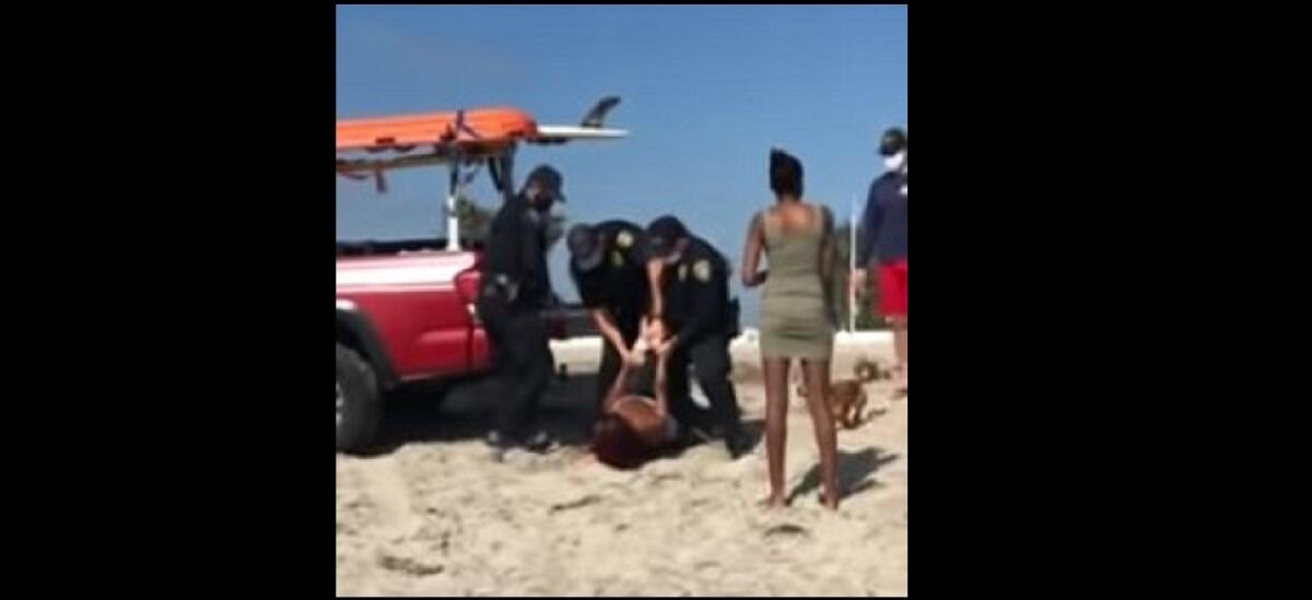 An image from video shows a woman being arrested in Ocean Beach after walking her unleashed dog on the sand May 1.