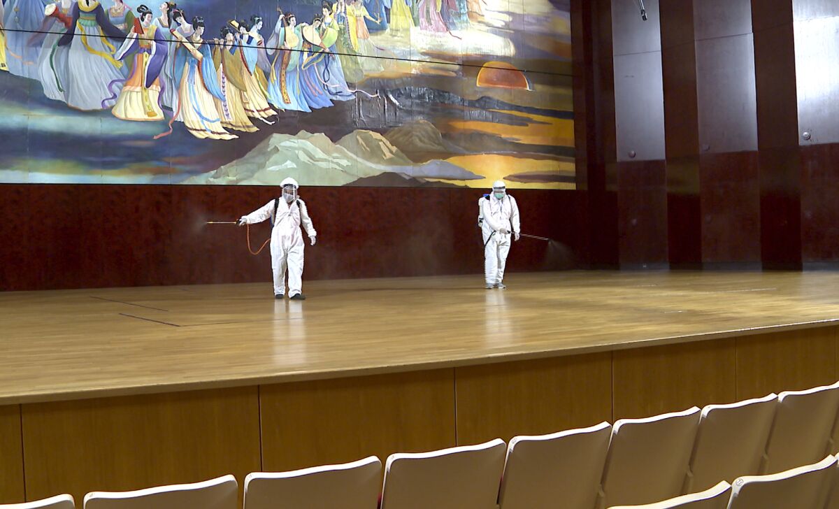 In this image made from video, a group of workers in hazmat suits disinfect stage inside the National Concert Hall in Taipei, Friday, March 6, 2020. Taiwan’s National Concert Hall cancels performance for disinfectant on Friday after an Australian composer who had visited was confirmed with coronavirus. (FTV via AP)