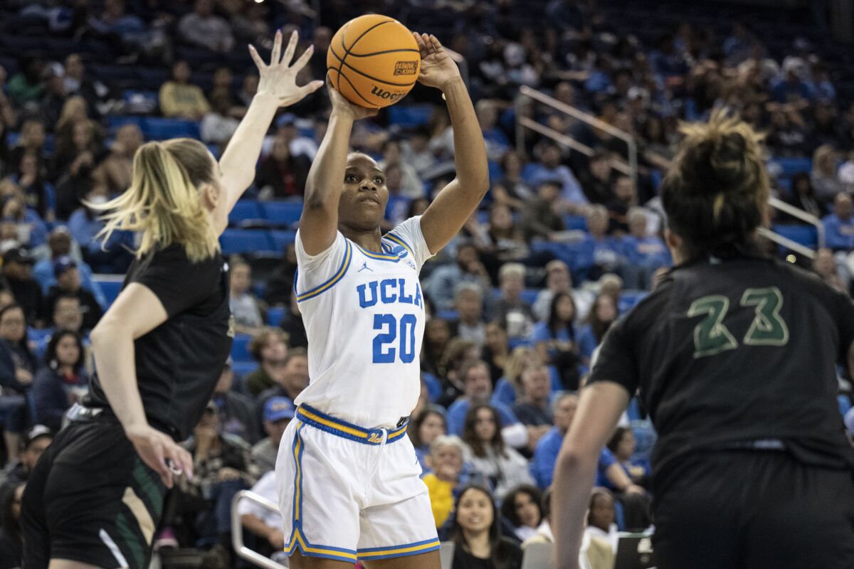 UCLA guard Charisma Osborne, center, shoots over Sacramento State guard Benthe Versteeg.