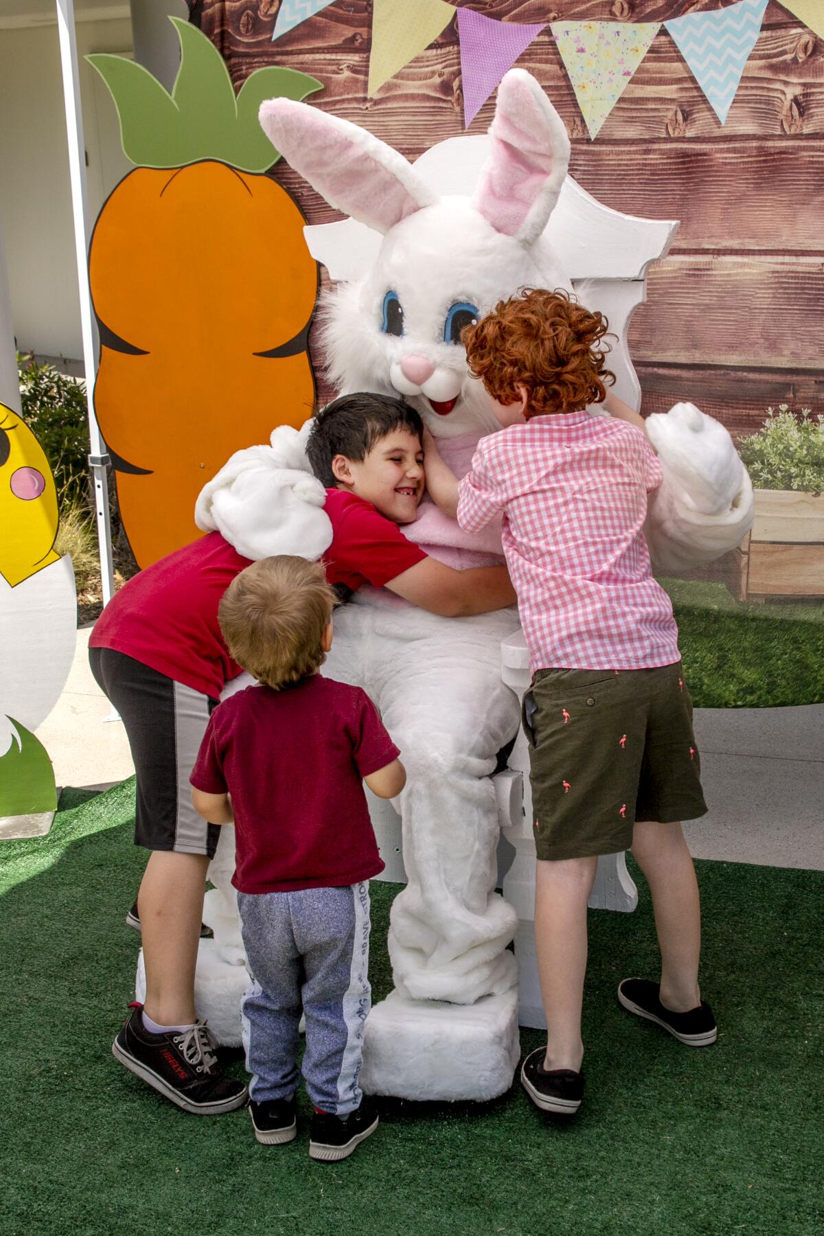 Alexander Eyre, 7, Arta Abraham, 7, and Allen Abraham, 2, give the Spring Bunny a big hug at SpringFest 2022. 