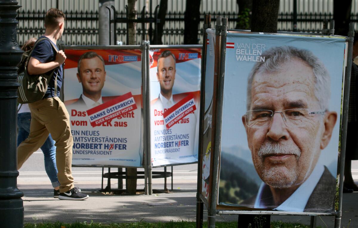 People walk between election posters for Alexander Van der Bellen, right, and Norbert Hofer, left, in Vienna on Monday.