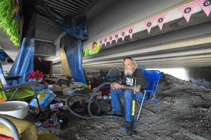 Bill "Tattoo" LeBlanc, 74, fixes a bicycle inner tube near his encampment in the Santa Ana River under the 5 Freeway in Orange. Hundreds of riverbed dwellers are at risk of drowning in heavy winter rains.