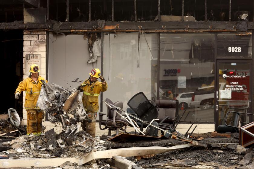 CULVER CITY, CA - SEPTEMBER 16, 2022 - - Firefighters clean up after an early morning fire that broke out in a strip mall where fire officials say 17 cats perished when fire raced through a feline overnight boarding facility and several other businesses in Culver City Saturday morning on September 16, 2022. Heavy smoke impacted at least half-dozen businesses along with the feline boarding facility where several cats were rescued. One firefighter took ill during the intense firefight and was taken to an area hospital in fair condition. There were no civilian injuries and a cause of the fire was under investigation. (Genaro Molina / Los Angeles Times)