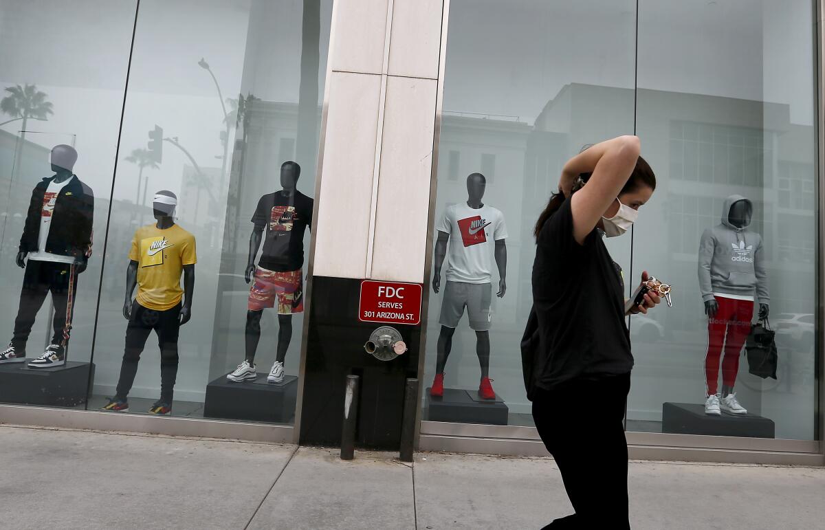 A woman walks by a shuttered luxury retail store in Santa Monica.