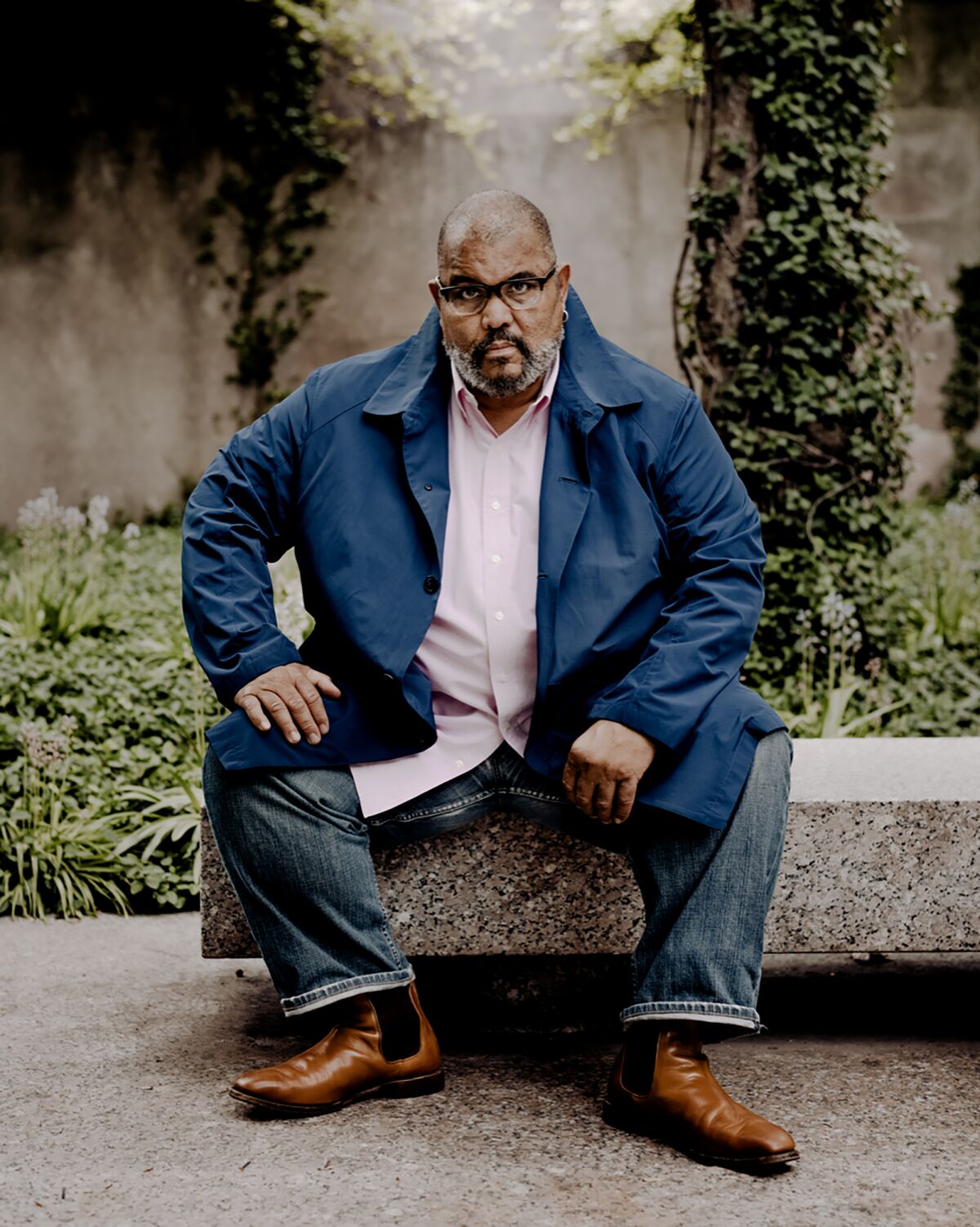 Dawoud Bey sits on a stone bench.