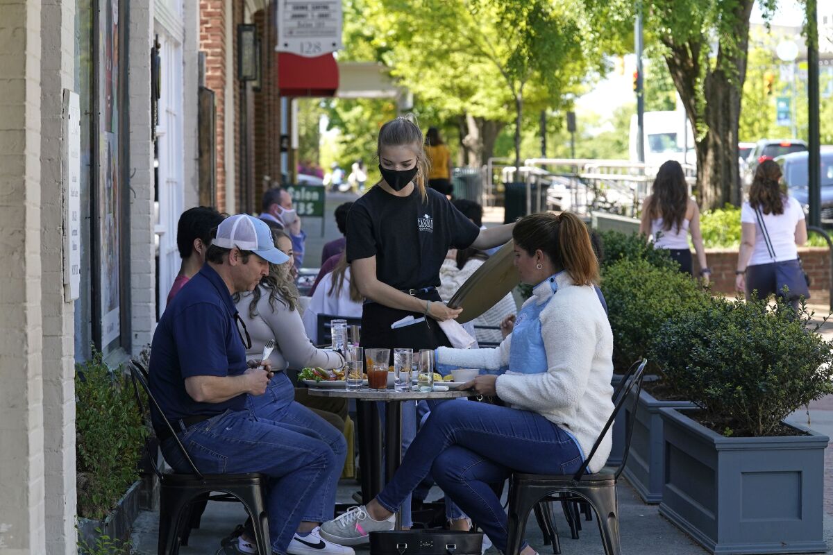 FILE - Patrons are assisted while dining along a sidewalk on Franklin Street in Chapel Hill, N.C., Friday, April 16, 2021. Growth in the services sector, where most Americans work, hit an all-time high in November, surpassing the previous record set in October. (AP Photo/Gerry Broome, File)