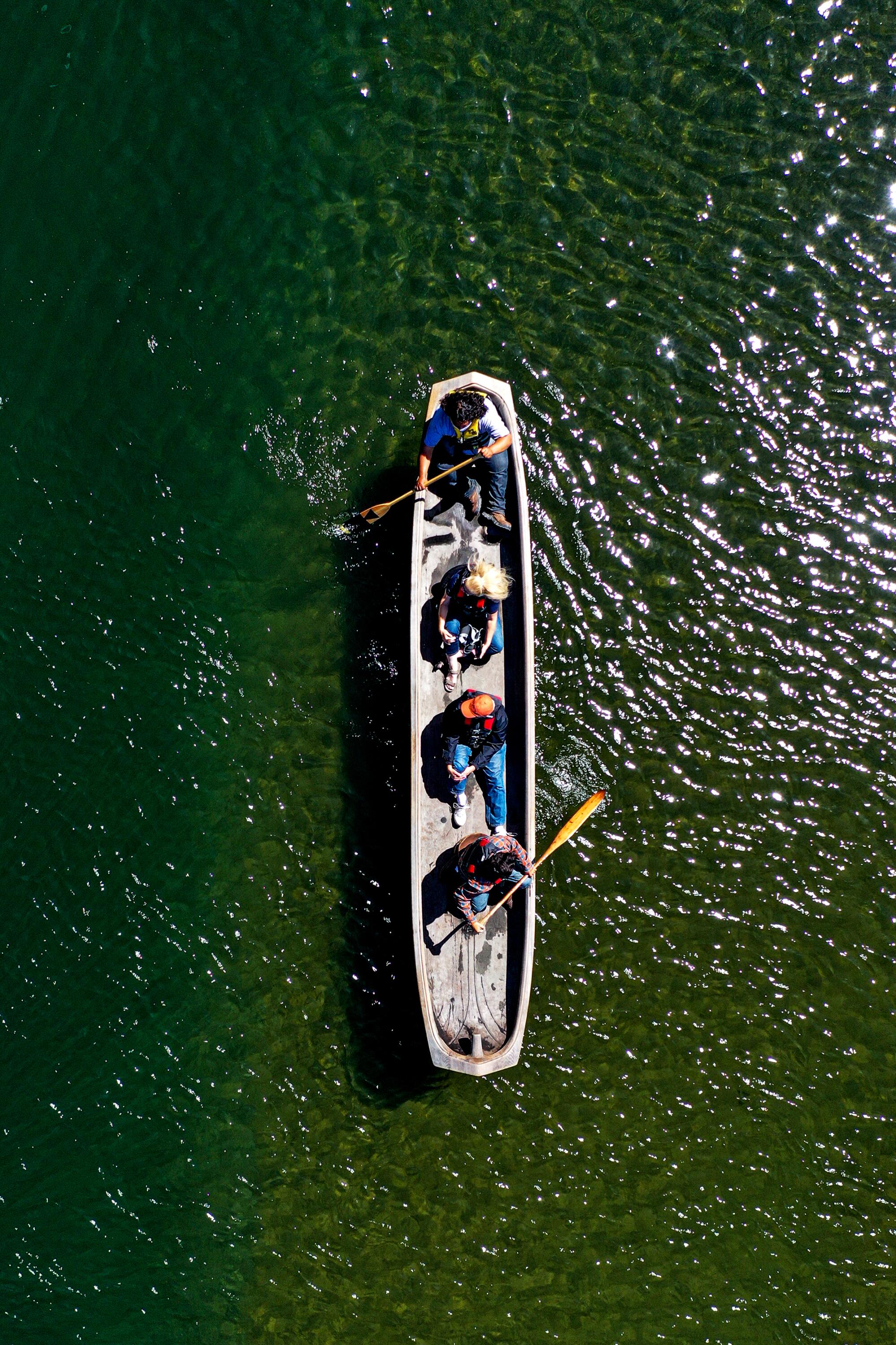 A Yurok canoe glides through the smooth water of the Klamath River.