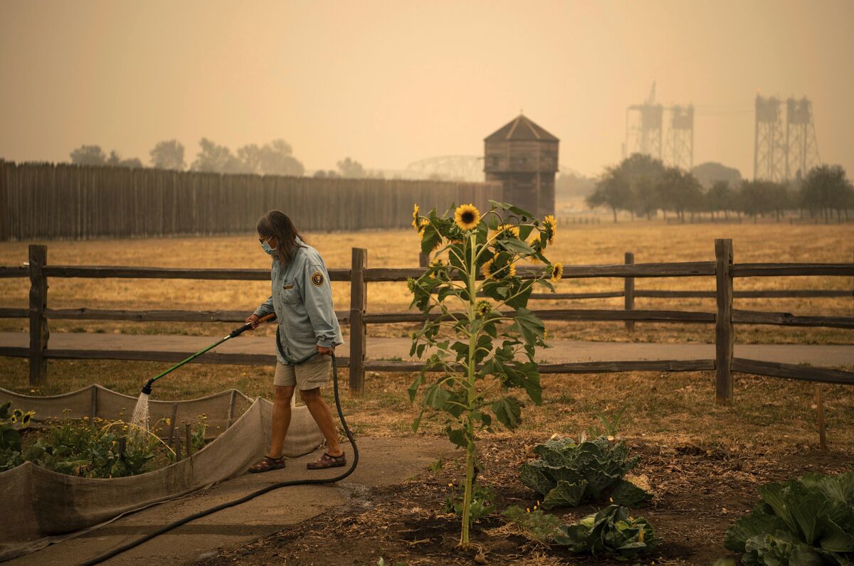 Volunteer Elizabeth Stoltz of Heisson waters the Fort Vancouver Garden in Vancouver, Wash., Friday, Sept. 11, 2020. Stolz said things were extra dried out because of the wind and smoke. "The wind sucks the life out of everything," she said. Stoltz said she is still not under evacuation from the Big Hollow Fire but her family made a plan in case it gets to that point. Clark County entered hazardous air-quality territory late Thursday as wildfire smoke traveling from other areas enveloped Southwest Washington. (Alisha Jucevic/The Columbian via AP)