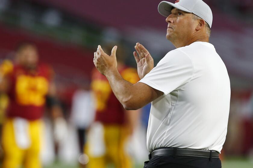 USC coach Clay Helton watches his team warm up before a game against Stanford at the Coliseum on Sept. 7.