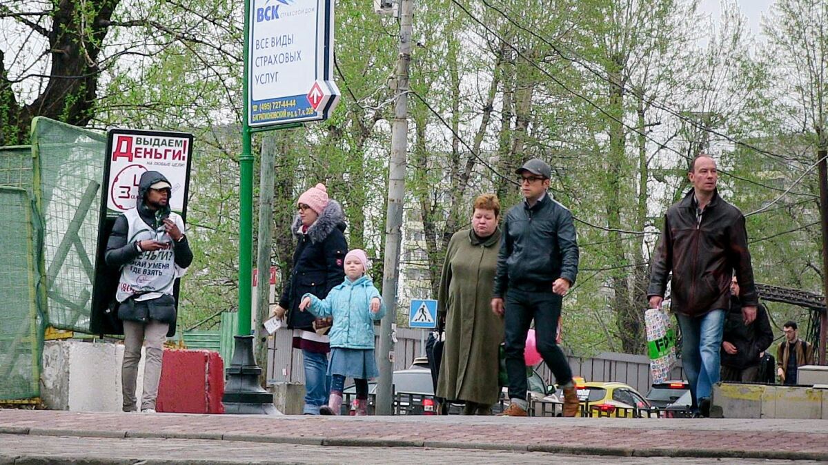 A young man with a billboard that reads, "Giving out money!" hands out leaflets advertising a payday lender in Moscow on April 27, 2016.