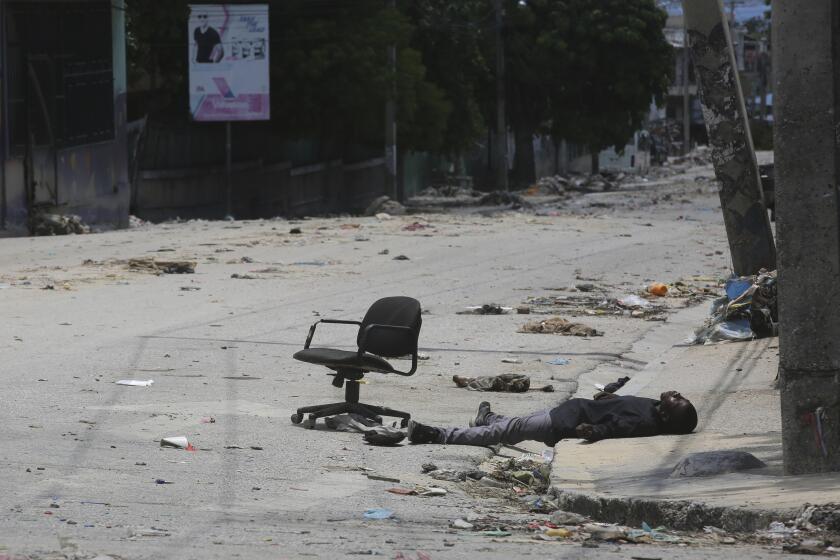 The body of a man lies on the side of an empty street, where an office chair sits, in downtown Port-au-Prince, Haiti, Friday, May 24, 2024. (AP Photo/Odelyn Joseph)