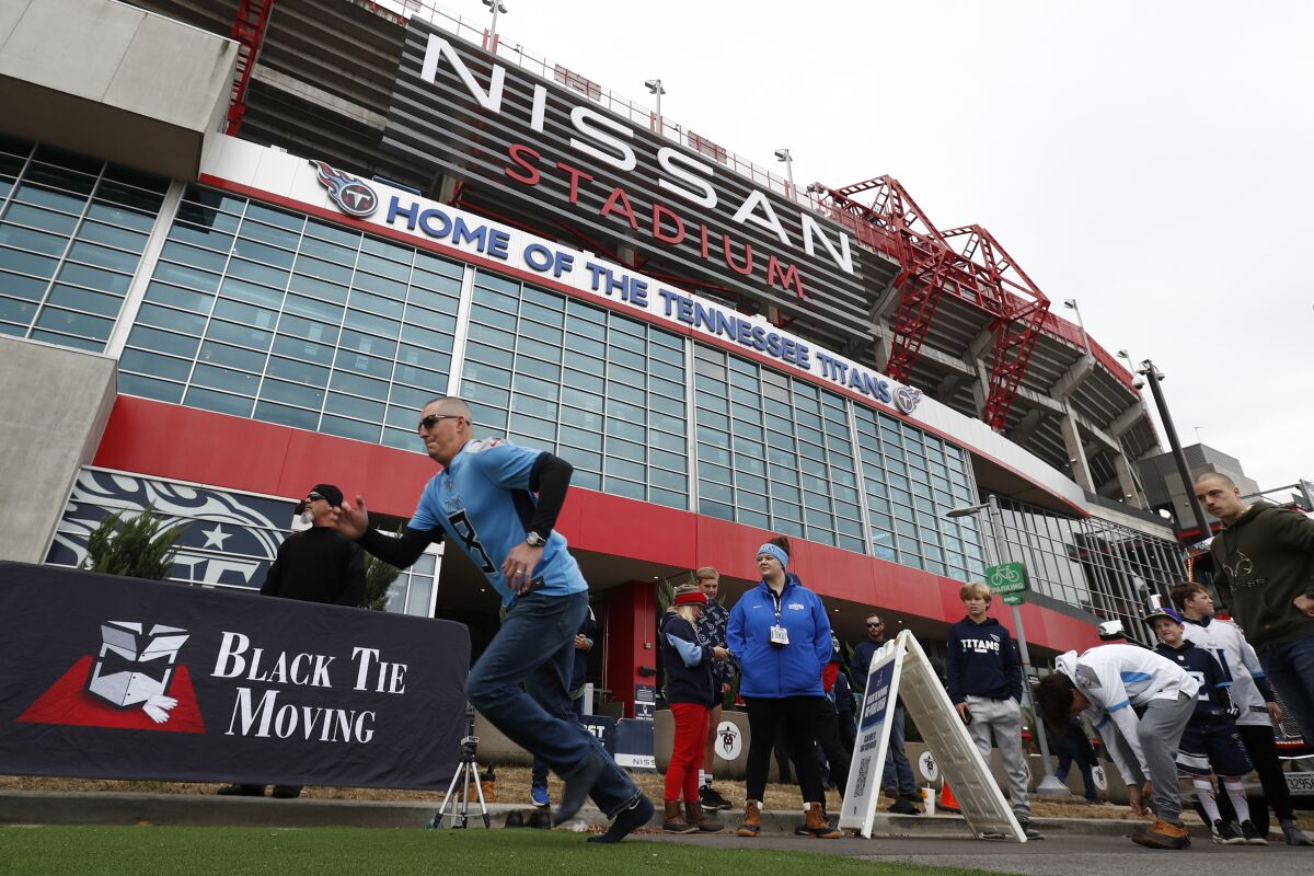 FILE - A Tennessee Titans fan runs a 40-yard dash outside Nissan Stadium before an NFL football game between the Titans and the Houston Texans on Nov. 21, 2021, in Nashville, Tenn. The Titans have gone from trying to modernize Nissan Stadium to working on plans for a brand-new stadium right next door after renovation costs more than doubled to $1.2 billion. (AP Photo/Wade Payne, File)