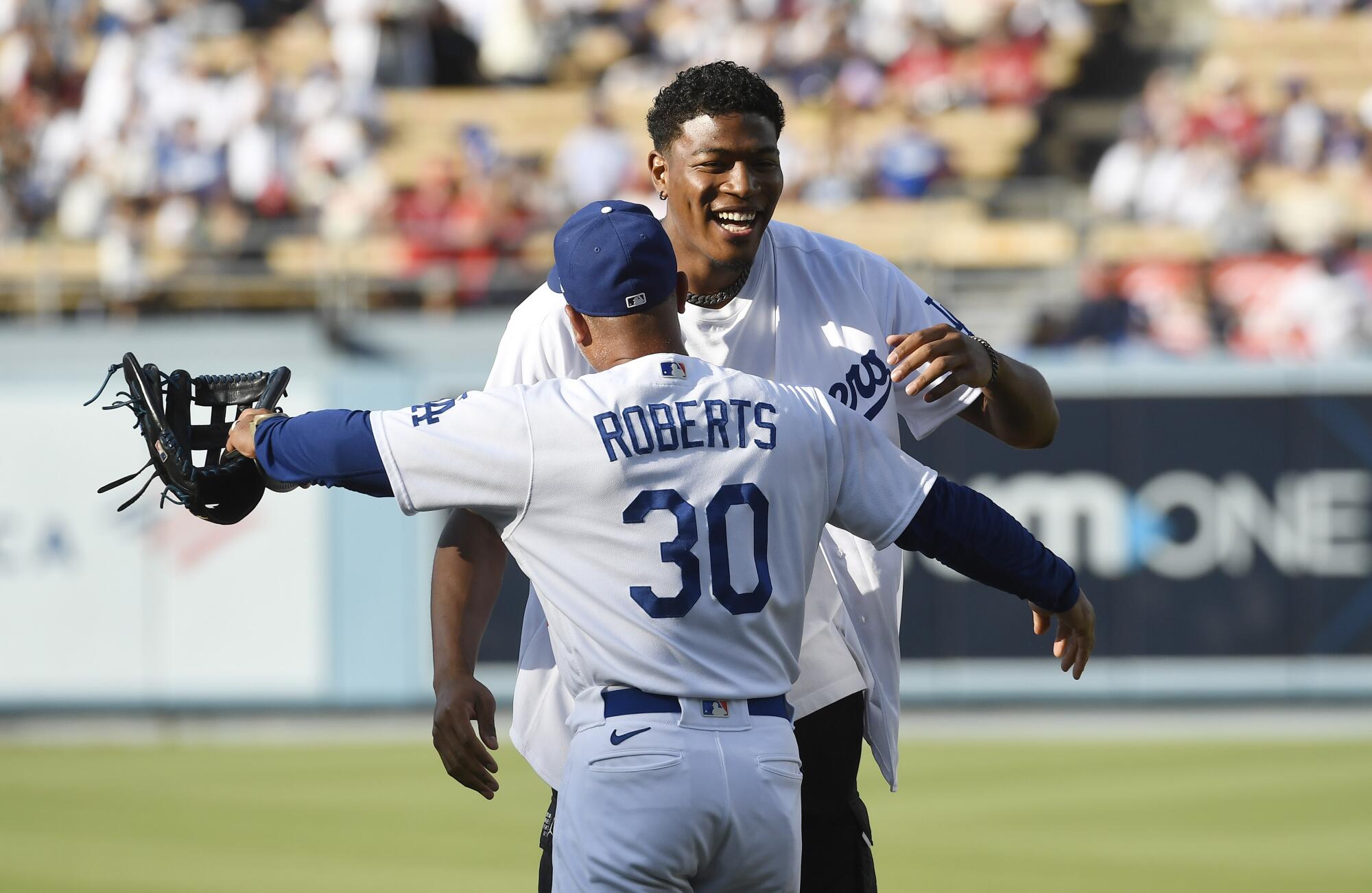 Rui Hachimura gets a hug from Dodgers manager Dave Roberts after throwing the ceremonial first pitch.