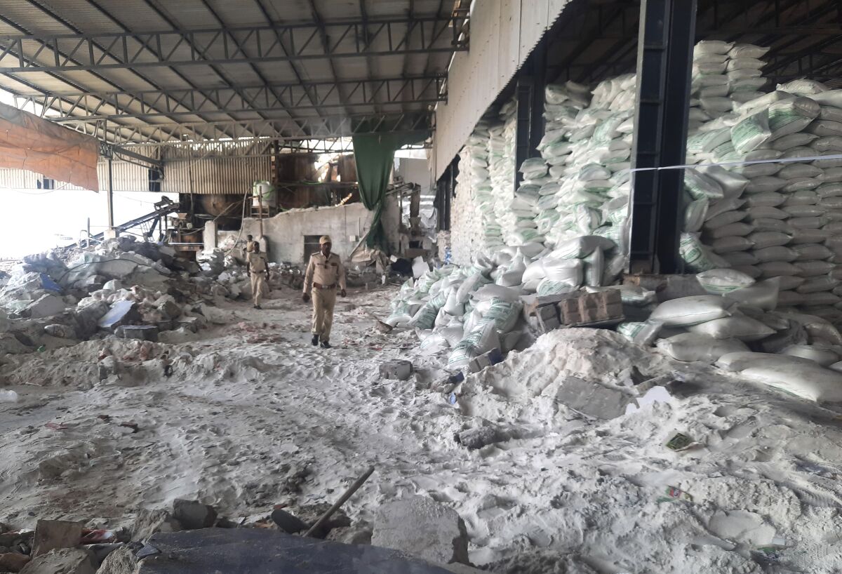Police inspect a salt packaging factory after its wall collapsed in Morbi district, 215 kilometers (135 miles) west of Gandhinagar, Gujarat state, India, Wednesday, May 18, 2022. At least a dozen workers were killed and more than a dozen were injured in the accident. (AP Photo)