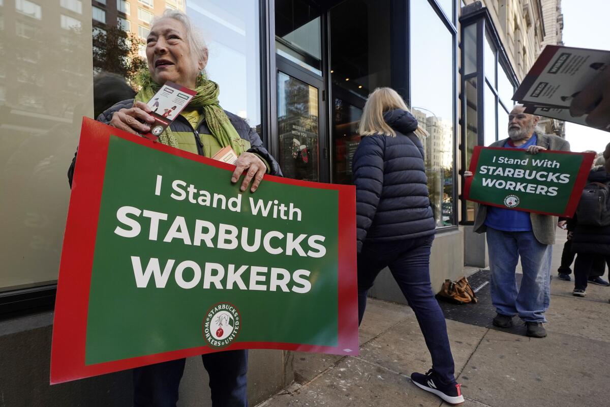 Arlene Geiger, izquierda, sostiene un cartel de apoyo a los trabajadores de Starbucks 