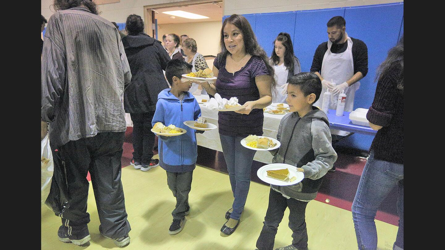 Darlene Rios, with her sons Noel, 8, and Noah, 7, of Glendale, bring their food to their table at the Salvation Army in Glendale where a pre-Thanksgiving meal was served to low-income families and homeless on Tuesday, November 21, 2017.