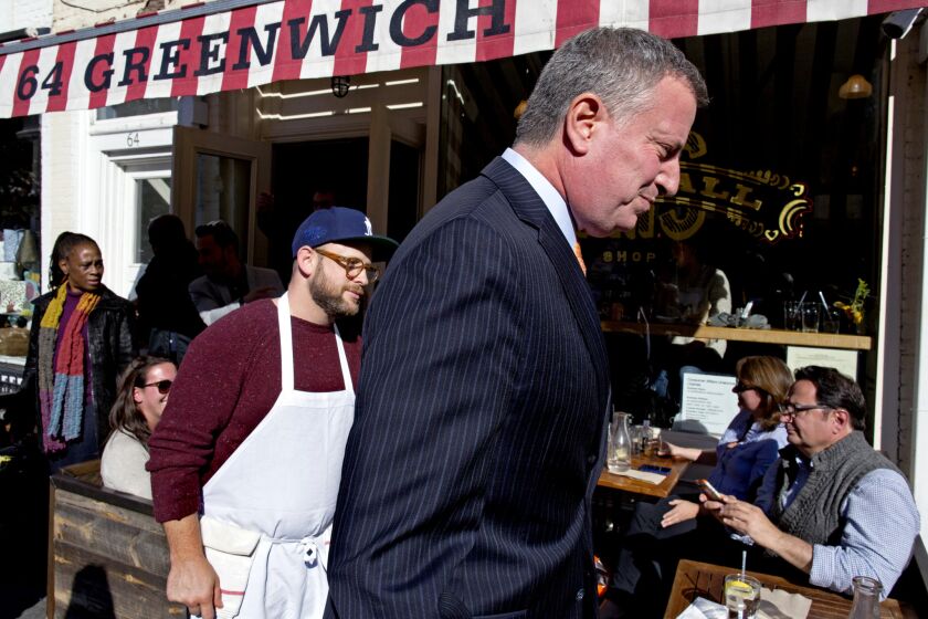New York City Mayor Bill de Blasio, right, walks on Saturday from the Meatball Shop restaurant, where Dr. Craig Spencer, an Ebola patient, ate just before he became ill.