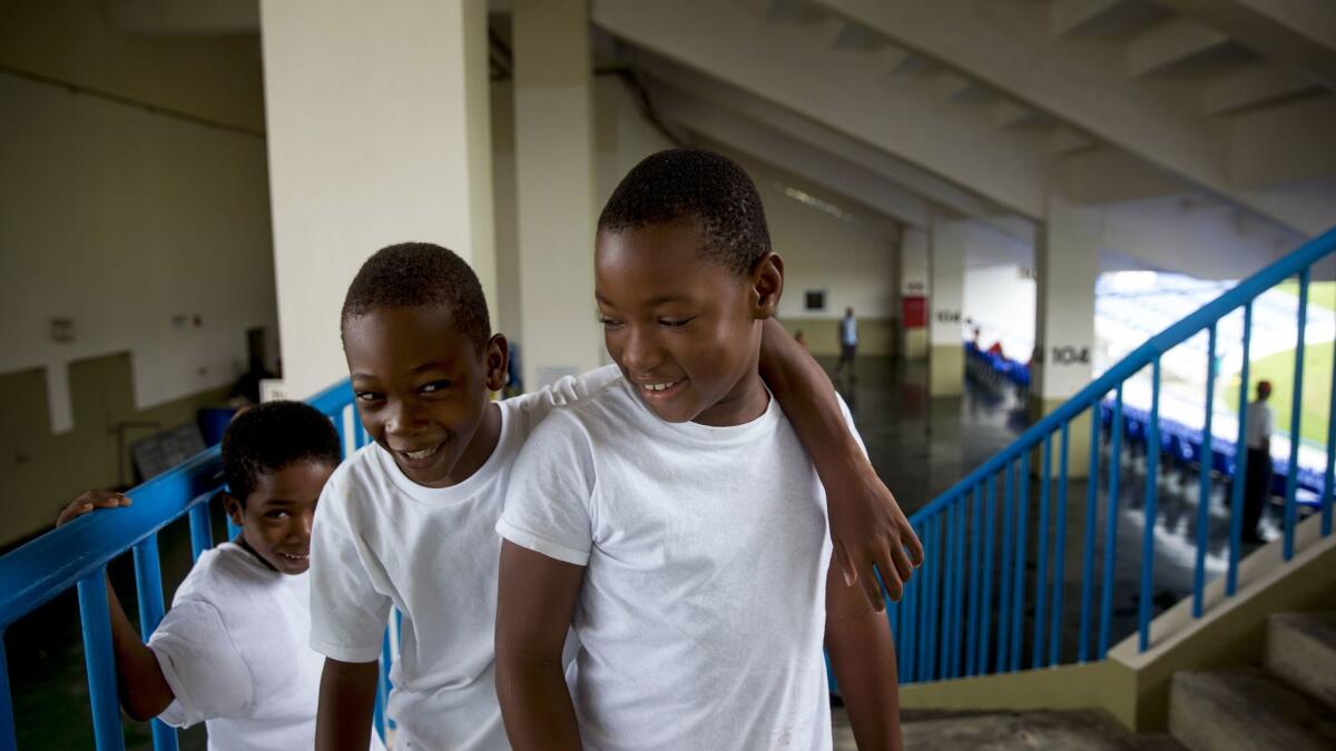Kadeam Bailey, 5, Blake Thomas, 9, and Eli Harris, 9, play in the shelter at the St. John's cricket stadium.