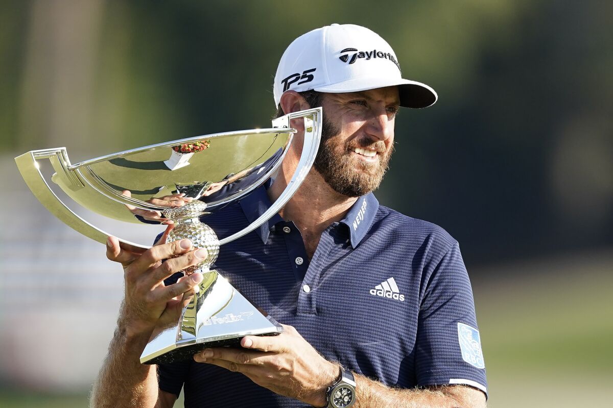 Dustin Johnson holds up the FedEx Cup trophy after winning the Tour Championship golf tournament on Monday, Sept. 7, 2020 at Lake Golf Club in Atlanta. (AP Photo/John Bazemore)