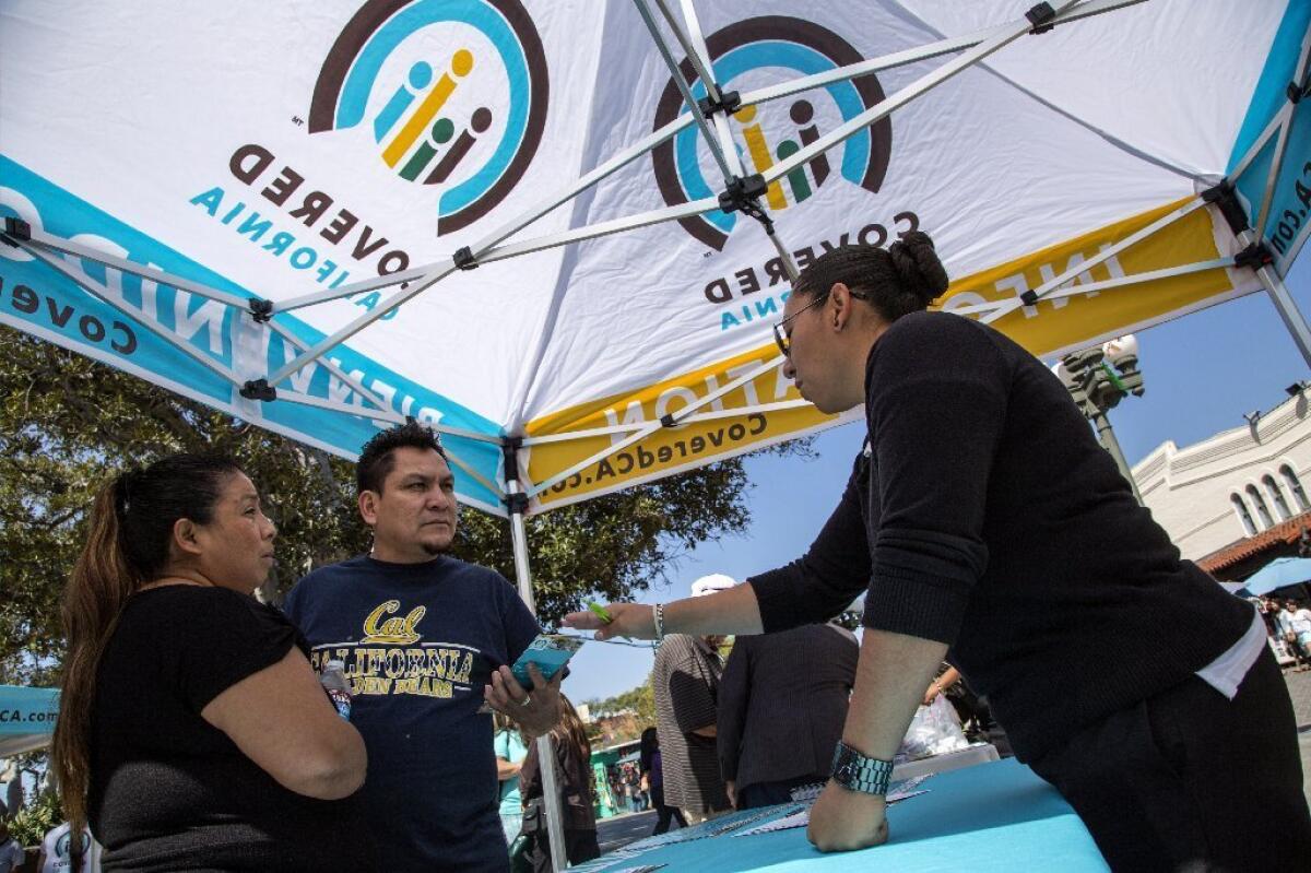 Ana Oliva and Felix Portillo of Los Angeles ask Valeria Lopez about Covered California insurance at an enrollment event in March in downtown L.A.