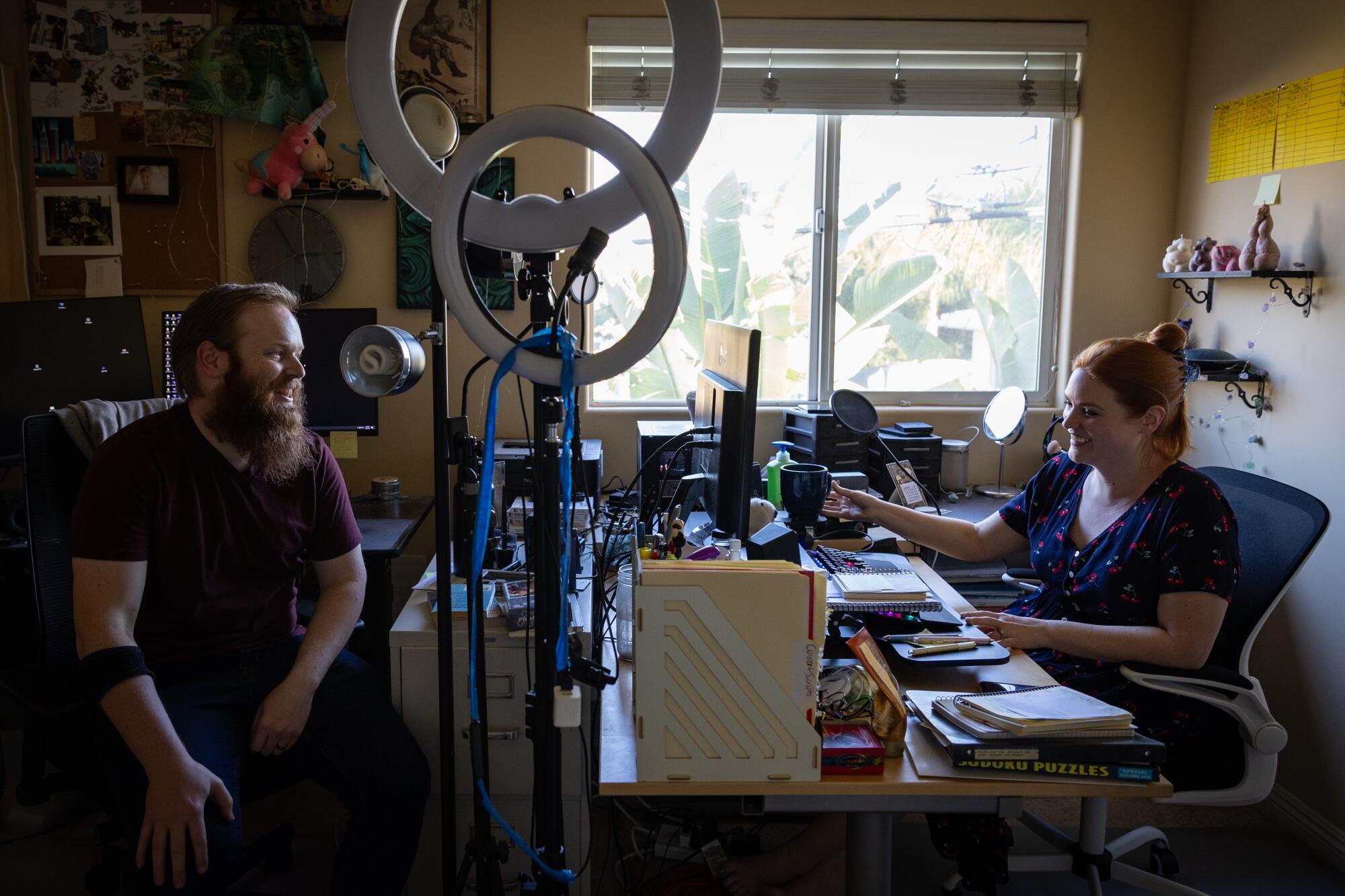 A woman and a man sit in chairs at a desk