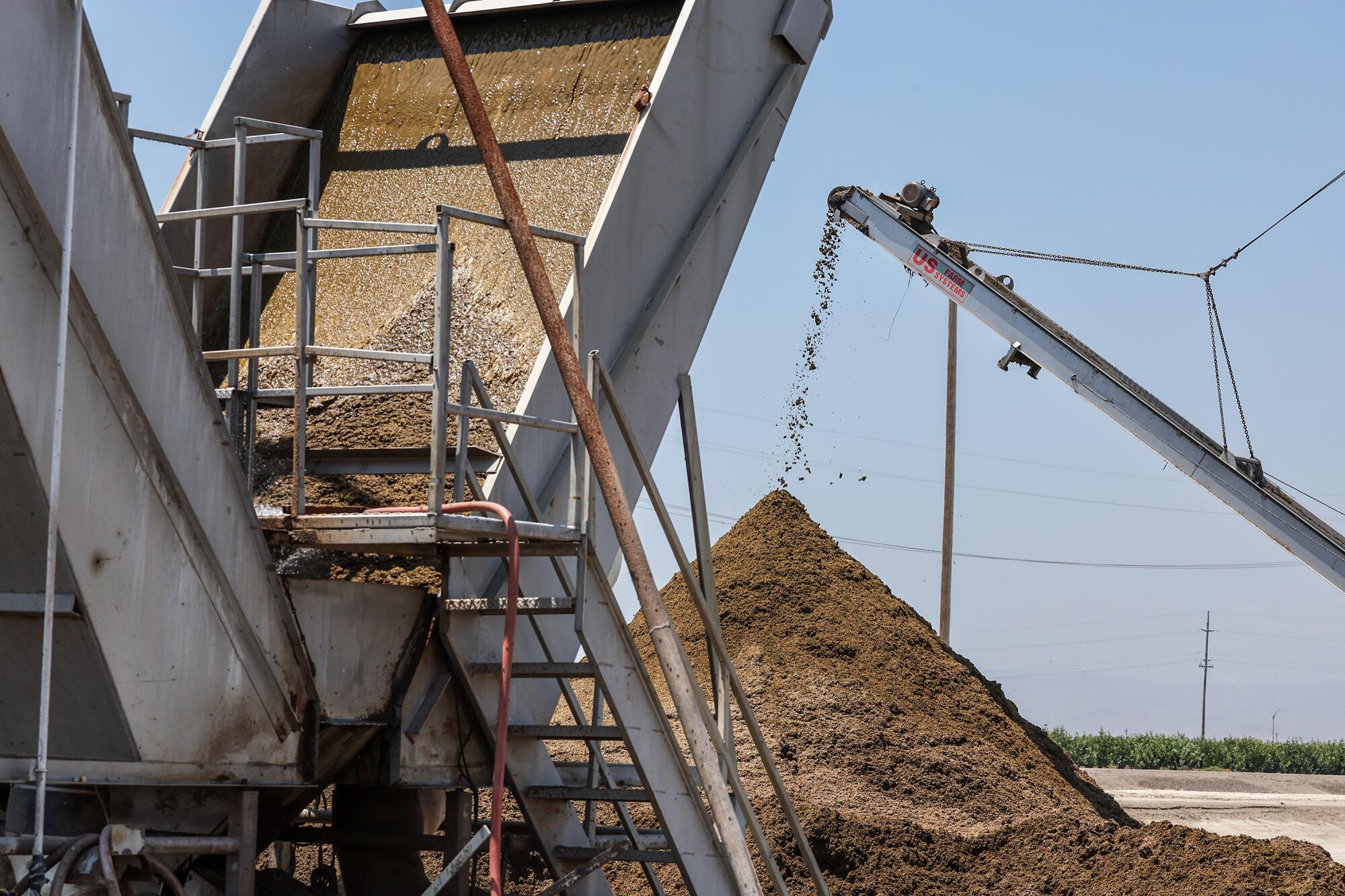 Conveyor belts dump dried manure into large piles. 