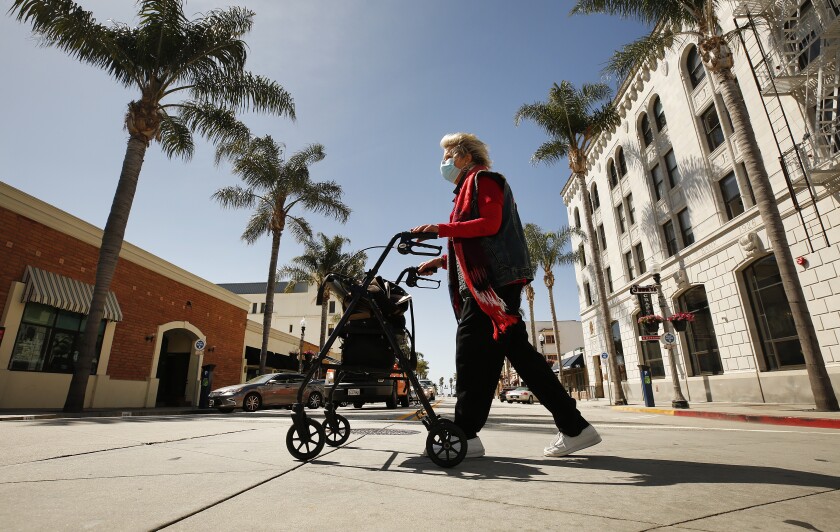 Cynthia Thompson crosses the street while wearing a mask in downtown Ventura.