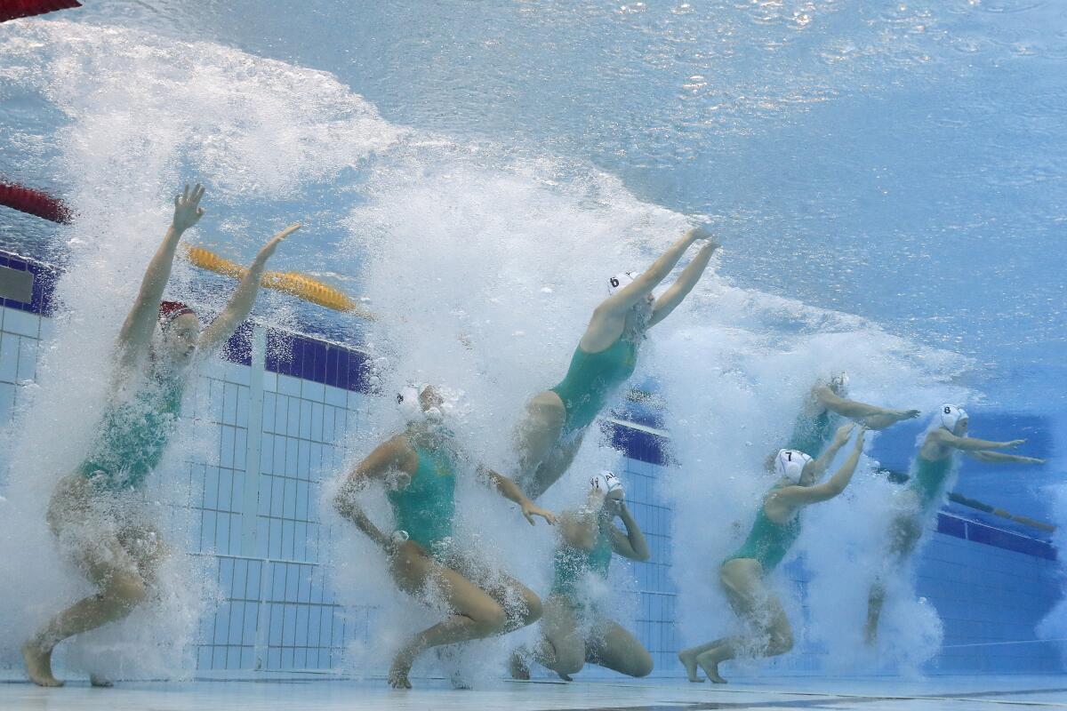 Water polo players jump into a pool at the 2022 FINA World Championships.
