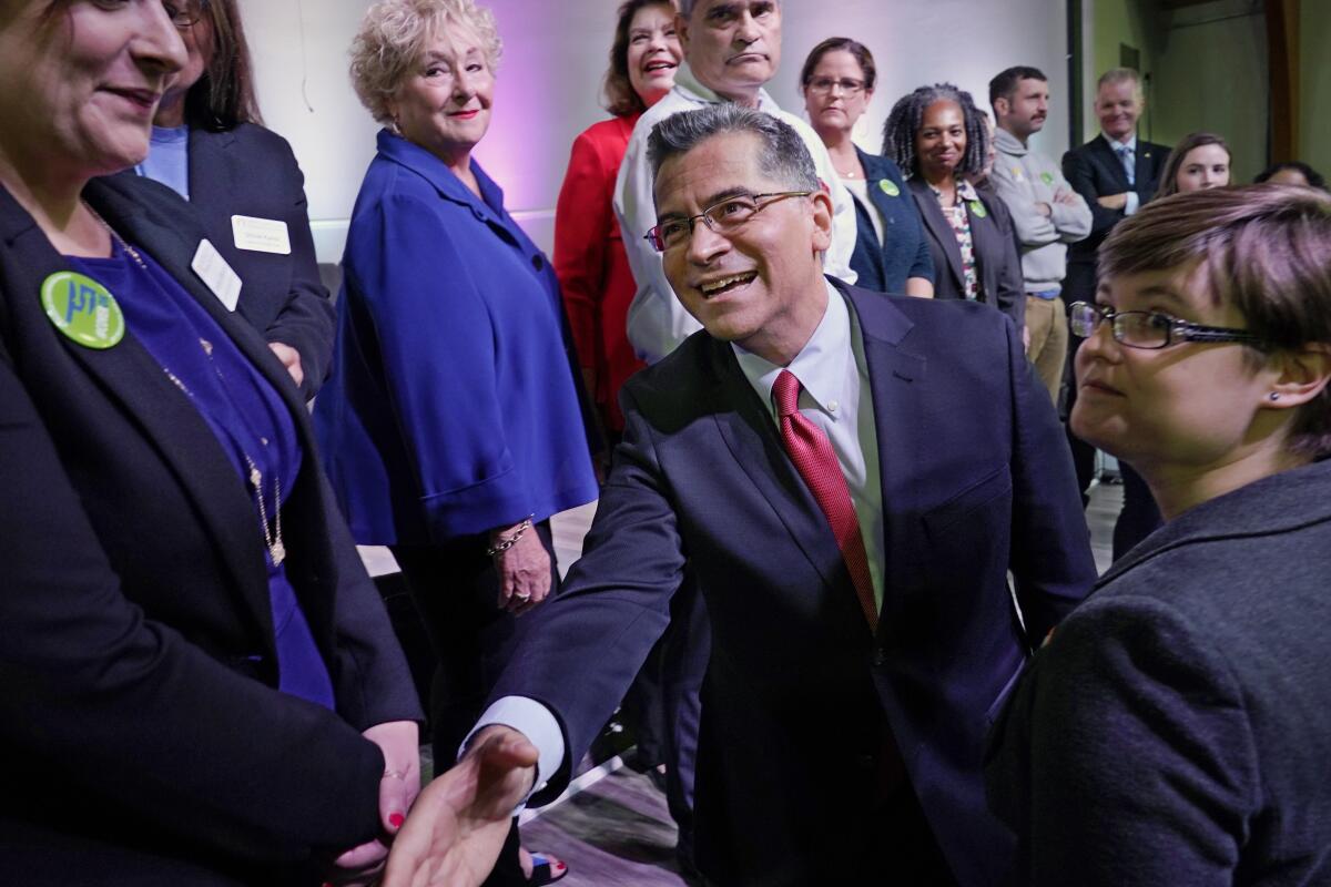 U.S. Department of Health and Human Services (HHS) Secretary Xavier Becerra, center, shakes hands with Oklahoma Medicaid advocates following a news conference Thursday, July 1, 2021, in Tulsa, Okla., as Oklahoma expands its Medicaid program. (AP Photo/Sue Ogrocki)