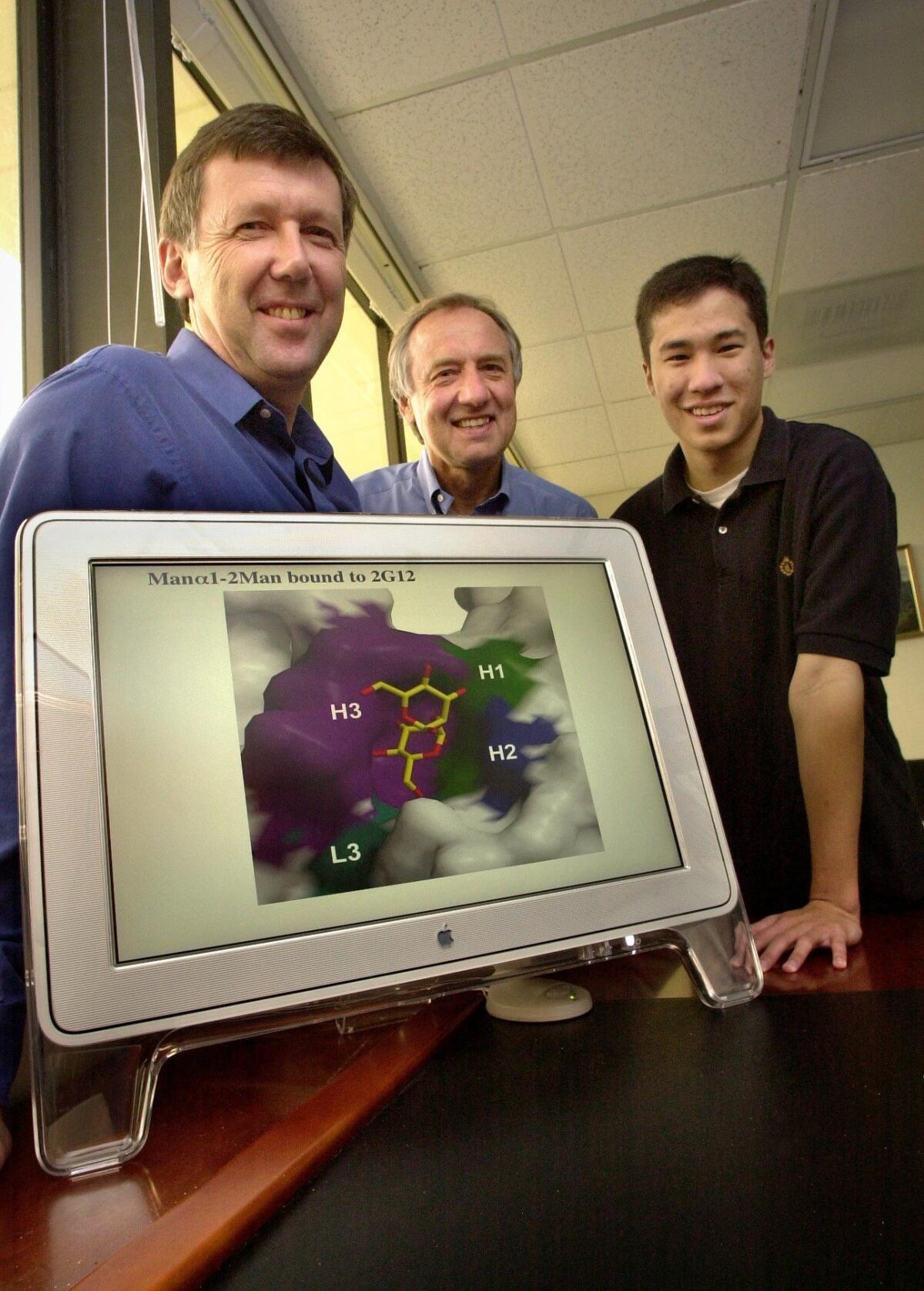 In this 2003 file photo, Scripps Research Institute scientists Dennis Burton, Ian Wilson, and Dan Calarese, left to right, stand behind a computer monitor displaying a rendition of the structure of a possible new AIDS antibody the group has identified. Dan Trevan