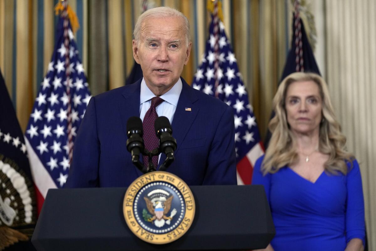 President Joe Biden speaks at a lectern, with a person behind him.