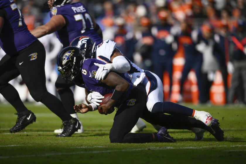 Lamar Jackson (8), quarterback de los Ravens de Baltimore, es capturado por el linebacker Jonathon Cooper (53), de los Broncos de Denver, en la primera mitad del juego de la NFL, el domingo 4 de diciembre de 2022, en Baltimore. Jackson salió lesionado de la rodilla. (AP Foto/Nick Wass)