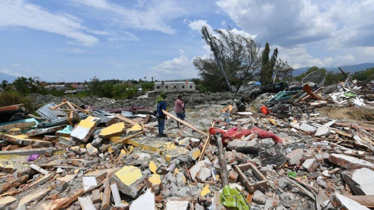 Two men examine debris near where their houses once were in Palu, Indonesia, on Oct. 4, 2018.