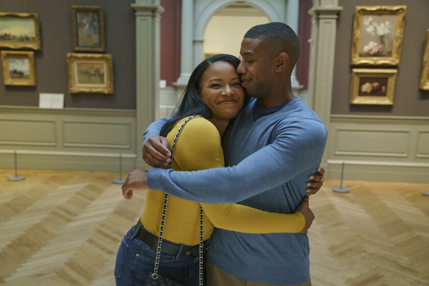 A man and woman hug and smile in a museum