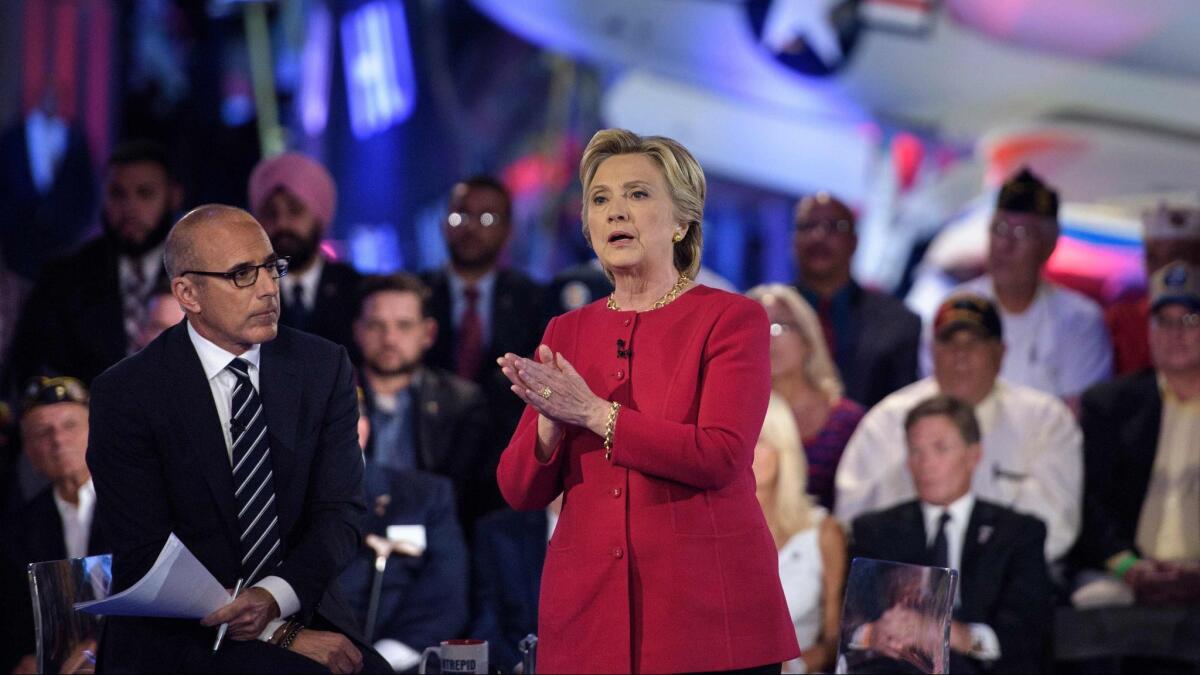Matt Lauer, then co-host of "The Today Show," listens as Democratic presidential nominee Hillary Clinton speaks aboard the aircraft carrier USS Intrepid on September 7, 2016 in New York.