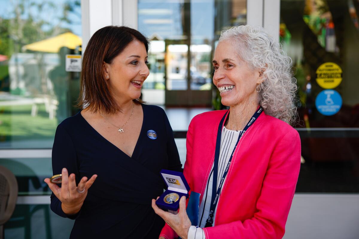 Mandy Cohen and Barbara Ferrer exchange commemorative tokens.