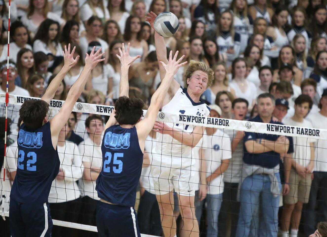 Newport Harbor High's Jack Higgs goes up high to put away a kill over Corona del Mar's Justin Browning (22) and Austin Chandler (25) in the Battle of the Bay rivalry at Newport Harbor Friday.