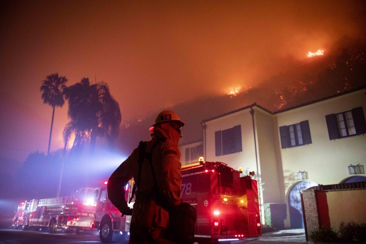 A firefighter watches flames approach the Mandeville Canyon neighborhood during the Getty fire on Monday in Los Angeles.